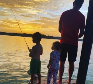 Sunset picture of Dr. Whitehead's children with Dad Andrew fishing off pier