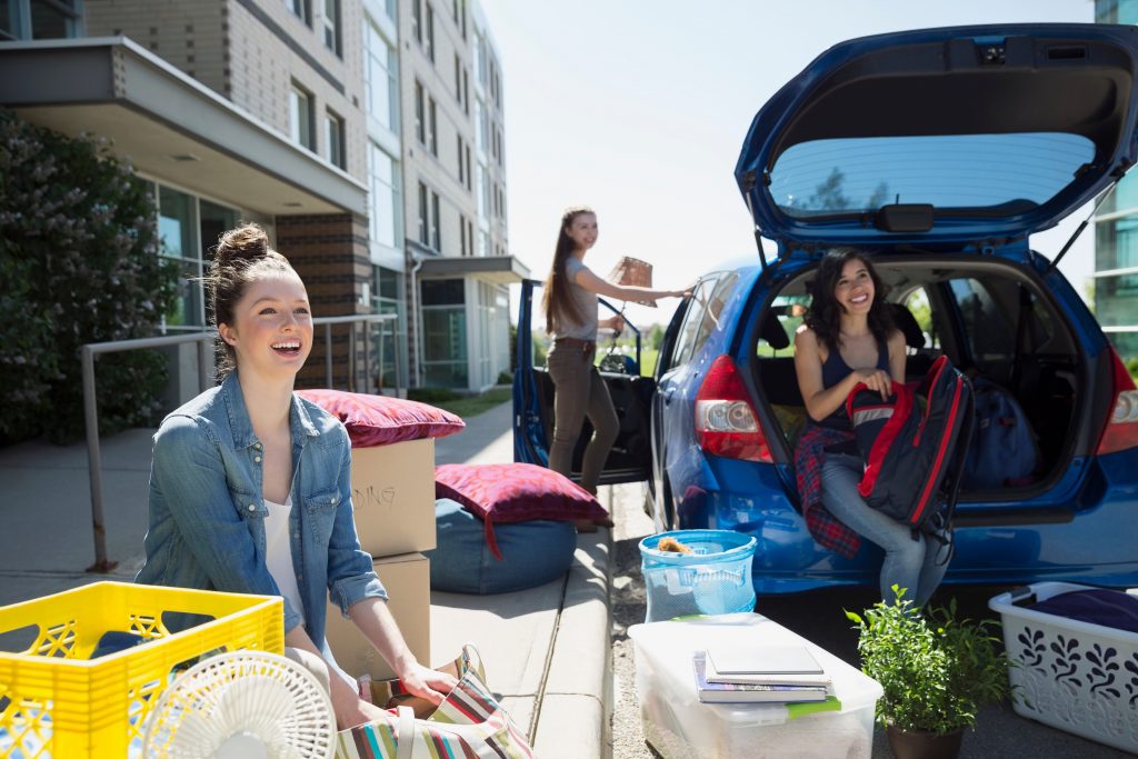 3 female college students unloading a car on dorm move-in day. Women's wellness means planning ahead.