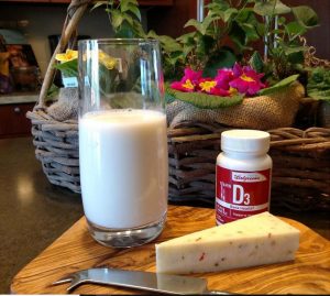 glass of milk, cheese wedge, and bottle of vitamin D supplements on a cheeseboard