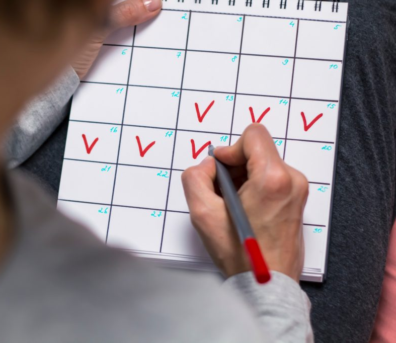 woman making red check marks on a calendar