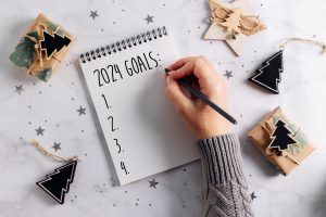 woman's hand writing new year's goals 2024
