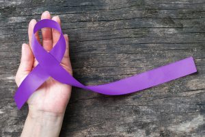 Hand holding purple ribbon for Pancreatic Cancer Awareness